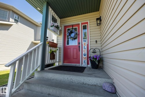 Inviting front entry featuring a red paneled door with a sidelight, concrete steps, and a white railing - 60 Leyland Way, Spruce Grove, AB 