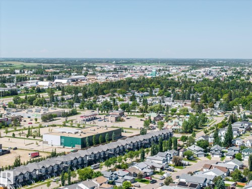 Expansive aerial perspective showcasing a residential district with diverse housing types, including a row of townhomes and detached properties - 60 Leyland Way, Spruce Grove, AB 