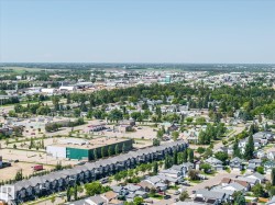 Expansive aerial perspective showcasing a residential district with diverse housing types, including a row of townhomes and detached properties - 