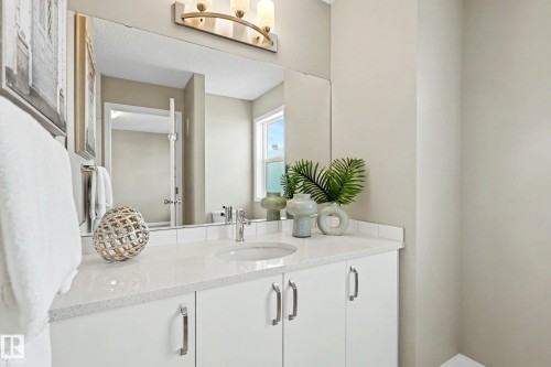 White vanity with a speckled countertop, undermount sink, and brushed chrome faucet - 53 2072 Wonnacott Way, Edmonton, AB 