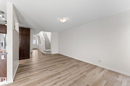 Spacious living area featuring wood-finish flooring, white walls, and a carpeted staircase - 12523 171 Avenue, Edmonton, AB 
