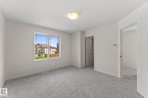 Bright interior room featuring a large window, light gray carpeting, and fresh white walls - 12523 171 Avenue, Edmonton, AB 