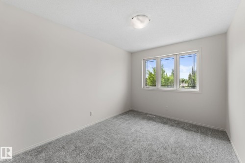 Bright room featuring a three-panel window, light-toned carpeting, and a ceiling-mounted flush light fixture - 12523 171 Avenue, Edmonton, AB 