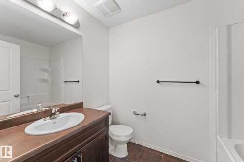 Bathroom featuring a vanity with an integrated sink, a dark wood-finish cabinet, and a brown countertop - 12523 171 Avenue, Edmonton, AB 