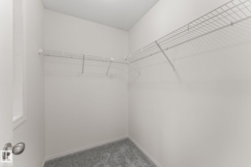Walk-in closet featuring white wire shelving, gray textured carpeting, and a window for natural light - 12523 171 Avenue, Edmonton, AB 