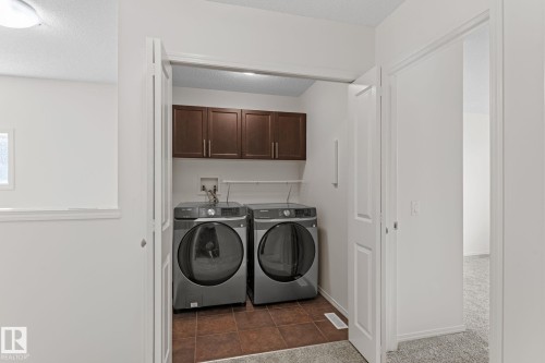 Dedicated laundry closet featuring a tile floor, built-in cabinetry, and a full-size washer and dryer - 12523 171 Avenue, Edmonton, AB 