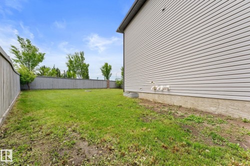 Expansive backyard featuring a manicured lawn, full perimeter fencing, and mature trees providing natural privacy - 12523 171 Avenue, Edmonton, AB 
