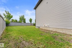 Expansive backyard featuring a manicured lawn, full perimeter fencing, and mature trees providing natural privacy - 