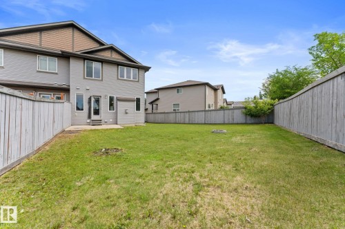 Spacious backyard featuring a manicured lawn, full fencing, and a concrete patio directly accessible from the dwelling - 12523 171 Avenue, Edmonton, AB 