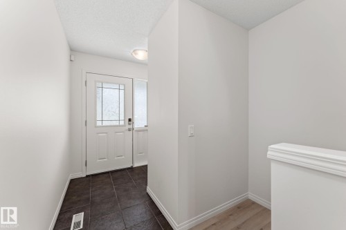 Entryway featuring a white paneled door with decorative glass inserts, a coordinating sidelight, and dark ceramic tile flooring - 12523 171 Avenue, Edmonton, AB 