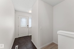 Entryway featuring a white paneled door with decorative glass inserts, a coordinating sidelight, and dark ceramic tile flooring - 