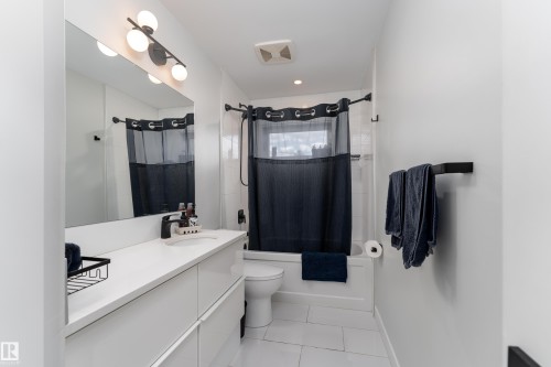 Contemporary bathroom featuring a spacious vanity with an integrated sink and matte black faucet - 10512 45 Street, Edmonton, AB 