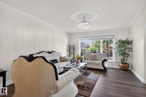 Spacious room featuring wood-finish flooring, crisp white walls, and crown molding - 4615 43A Avenue, Edmonton, AB - Indoor Photo Showing Living Room