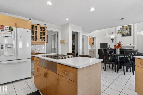 Kitchen island featuring a cooktop, white countertop, and natural wood cabinetry - 4615 43A Avenue, Edmonton, AB - Indoor Photo Showing Other Room