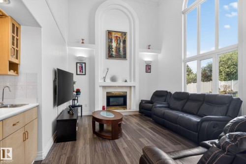 Spacious living area featuring high ceilings, tall arched windows, and wood-finish flooring - 4615 43A Avenue, Edmonton, AB - Indoor Photo Showing Living Room With Fireplace