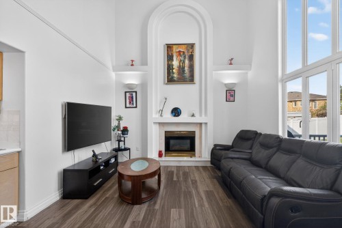 Living area featuring a floor-to-ceiling fireplace with an arched surround, tall windows, wood-finish flooring, and built-in wall sconces - 4615 43A Avenue, Edmonton, AB - Indoor Photo Showing Living Room With Fireplace