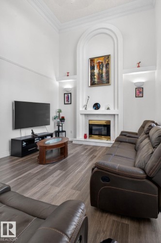 Living area featuring a floor-to-ceiling arched fireplace with an electric insert, integrated display niches with sconce lighting, and crown molding - 4615 43A Avenue, Edmonton, AB - Indoor With Fireplace