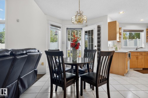 Dining area with outdoor access featuring a gold-tone chandelier, white tiled flooring, and French doors - 4615 43A Avenue, Edmonton, AB - Indoor Photo Showing Dining Room
