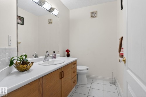 Bathroom featuring a vanity with a white countertop, an integrated sink, and wood-finish cabinetry - 4615 43A Avenue, Edmonton, AB - Indoor Photo Showing Bathroom