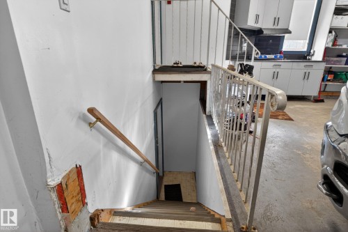 Stairwell leading to lower level featuring a wooden handrail and metal railing - 4615 43A Avenue, Edmonton, AB - Indoor Photo Showing Other Room