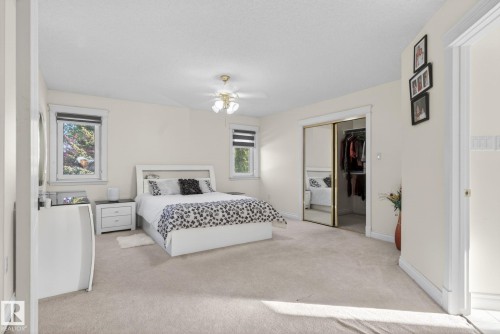 Carpeted bedroom with two windows and a ceiling fan light fixture - 4615 43A Avenue, Edmonton, AB - Indoor Photo Showing Bedroom