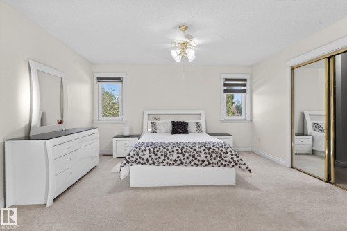 Carpeted room featuring two windows with roller blinds, a ceiling fan with light fixture, and a mirrored sliding closet door - 4615 43A Avenue, Edmonton, AB - Indoor Photo Showing Bedroom