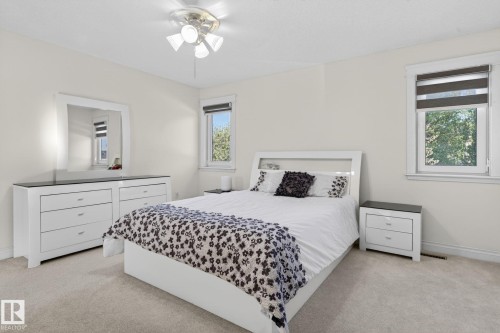 Carpeted bedroom featuring neutral wall paint, two windows with roller blinds, and a ceiling fan with integrated lighting - 4615 43A Avenue, Edmonton, AB - Indoor Photo Showing Bedroom