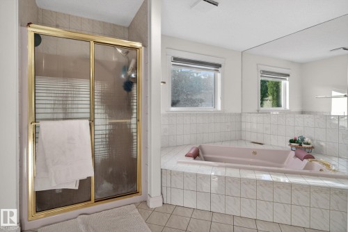 Soaking tub with tiled surround, two windows, and a full-wall mirror - 4615 43A Avenue, Edmonton, AB - Indoor Photo Showing Bathroom