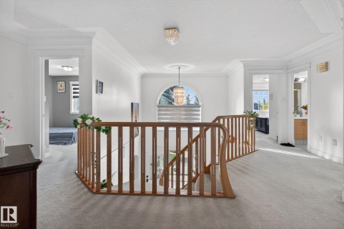 Spacious upper landing featuring light-toned carpeting, a wood-finish staircase railing, and an arched window - 4615 43A Avenue, Edmonton, AB - Indoor Photo Showing Other Room