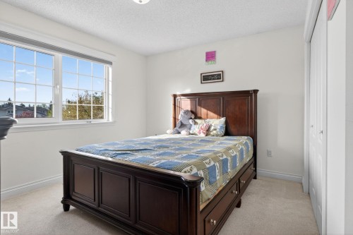Spacious room featuring a large grid-patterned window, light-colored carpeting, white baseboards, and a bi-fold closet - 4615 43A Avenue, Edmonton, AB - Indoor Photo Showing Bedroom