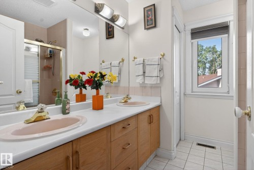 Bathroom featuring a double vanity with wood-finish cabinetry, a large mirror, and overhead strip lighting - 4615 43A Avenue, Edmonton, AB - Indoor Photo Showing Bathroom