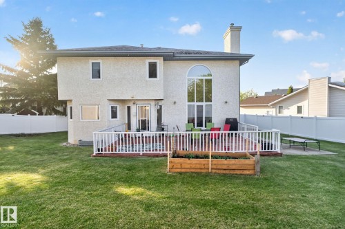 Expansive backyard featuring a manicured lawn, a large deck with white railings, and a wood-finish raised garden bed - 4615 43A Avenue, Edmonton, AB - Outdoor