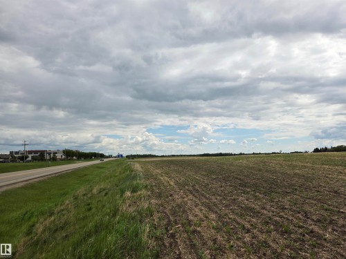 Expansive agricultural field with tilled soil, bordering a paved roadway and a grassy verge - 24209 Hwy 625, Beaumont, AB 