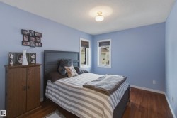 Bedroom featuring wood-finish flooring, light blue walls, and a recessed ceiling light fixture - 