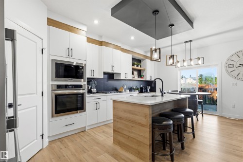 Bright kitchen featuring white cabinetry and wood-finish flooring - 7 Tenor Link, Spruce Grove, AB 