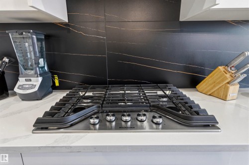 Stainless steel gas cooktop with five burners set into a white countertop - 7 Tenor Link, Spruce Grove, AB 