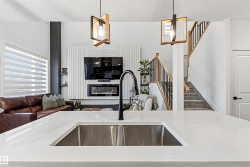 Kitchen island featuring a double basin stainless steel sink with a matte black gooseneck faucet - 7 Tenor Link, Spruce Grove, AB 