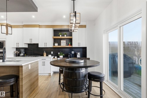 Modern kitchen featuring light wood-finish flooring and a kitchen island with a light countertop - 7 Tenor Link, Spruce Grove, AB 