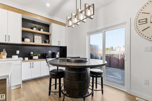 Kitchen space featuring wood-finish flooring and a sliding glass door leading to an outdoor deck - 7 Tenor Link, Spruce Grove, AB 