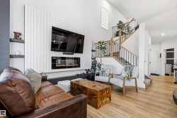 Living area featuring a vertical slat accent wall with an integrated linear fireplace, built-in shelving, and light wood-finish flooring - 