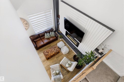 Living area with light wood-finish flooring and a contemporary fireplace feature wall - 7 Tenor Link, Spruce Grove, AB 