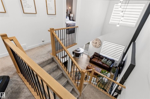 Open-concept living space featuring a two-story ceiling, multiple windows with horizontal blinds, and a durable wood-finish flooring - 7 Tenor Link, Spruce Grove, AB 