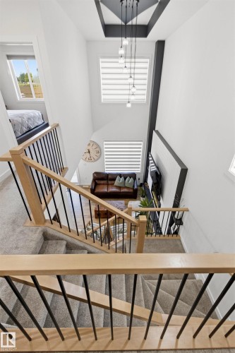 Multi-level interior showcasing an open staircase with wood-finish handrails and black metal spindles - 7 Tenor Link, Spruce Grove, AB 