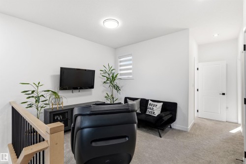 Upper-level landing featuring light gray carpeting, white walls, and a modern flush-mount ceiling light - 7 Tenor Link, Spruce Grove, AB 