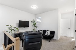 Upper-level landing featuring light gray carpeting, white walls, and a modern flush-mount ceiling light - 