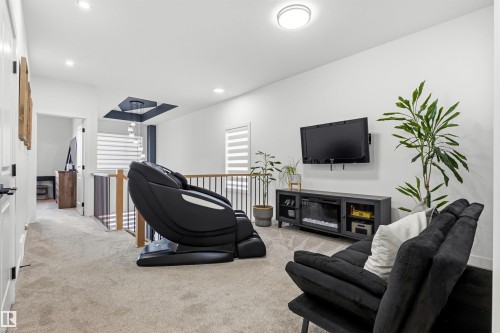 Loft space featuring neutral carpeting, white walls, and a contemporary ceiling light fixture - 7 Tenor Link, Spruce Grove, AB 