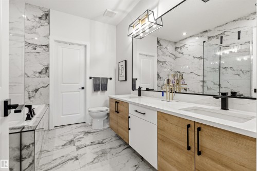 Contemporary bathroom featuring a dual vanity with wood-finish cabinetry, white countertops, and matte black fixtures - 7 Tenor Link, Spruce Grove, AB 
