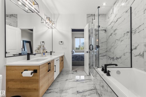 Spacious bathroom featuring marble-patterned floor and wall tile, a double vanity with wood-finish cabinetry, a glass-enclosed shower, and a built-in soaking tub with black fixtures - 7 Tenor Link, Spruce Grove, AB 