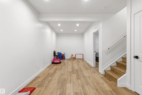 Spacious open area featuring wood-finish flooring, recessed lighting, and a neutral color palette - 7 Tenor Link, Spruce Grove, AB 