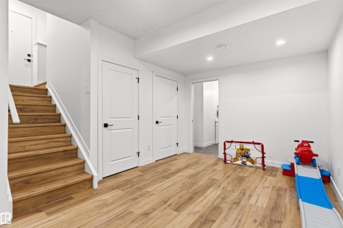 Open-concept area featuring wood-finish flooring, white trim, recessed lighting, and a staircase with white railings - 7 Tenor Link, Spruce Grove, AB 